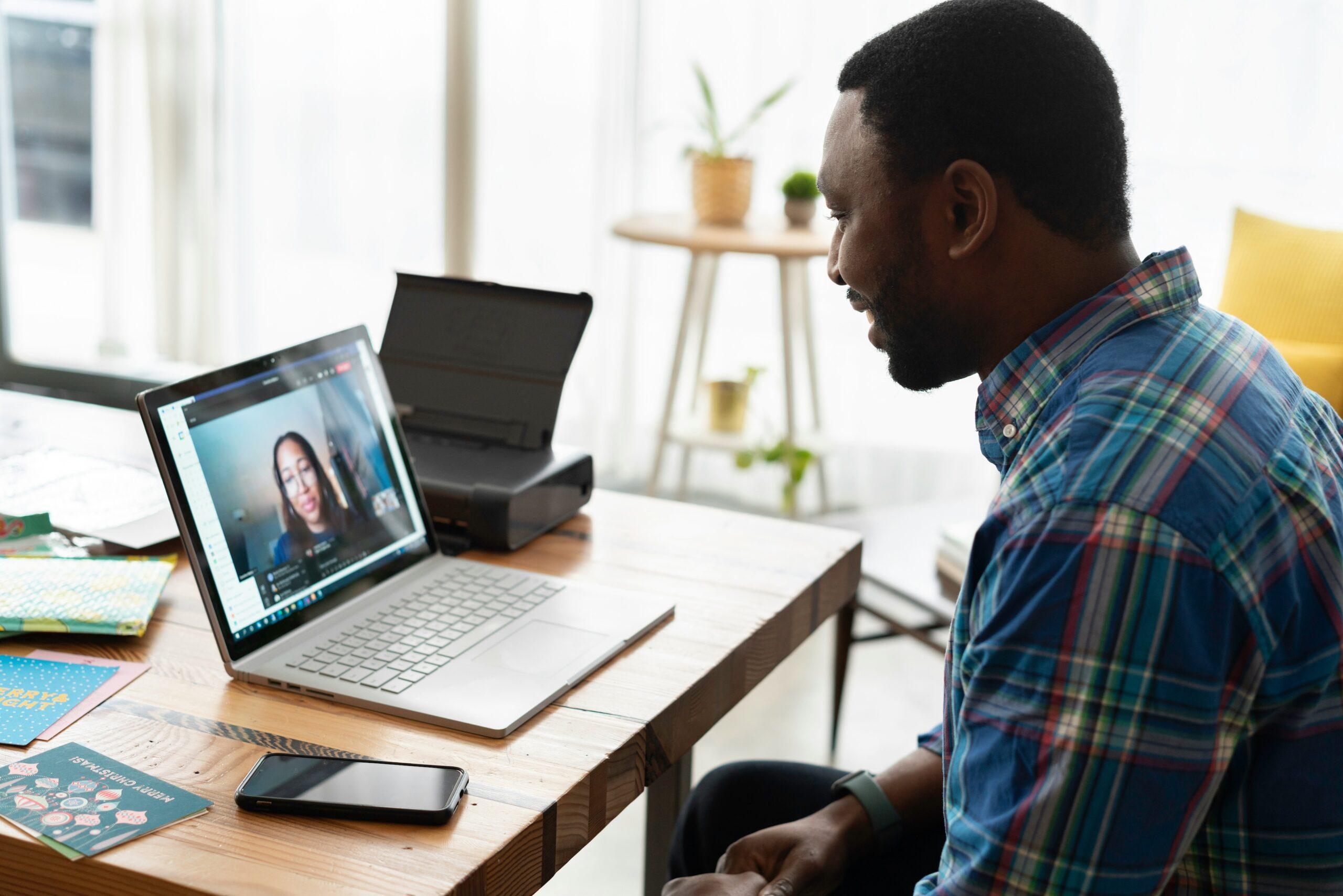 Man speaking to a woman via a laptop screen on a desk setup