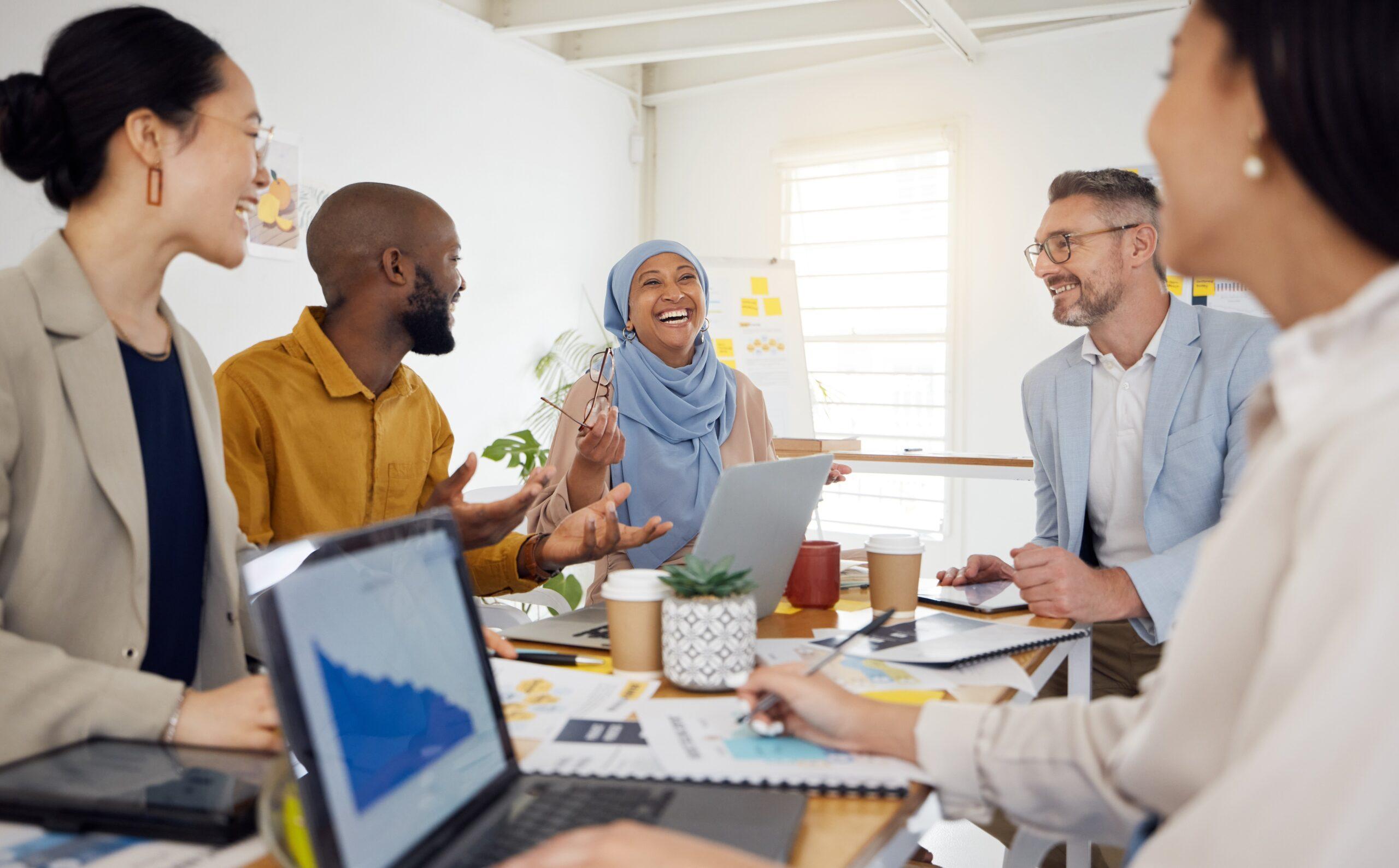 group of employees sitting around a table laughing and chatting