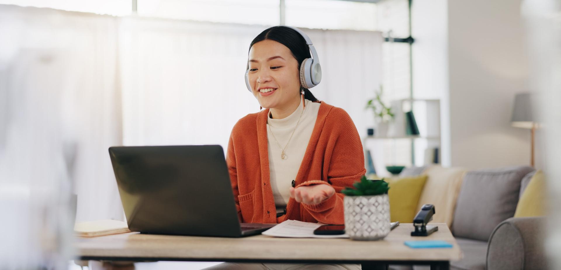 Woman on video call with work from home laptop and headphones.
