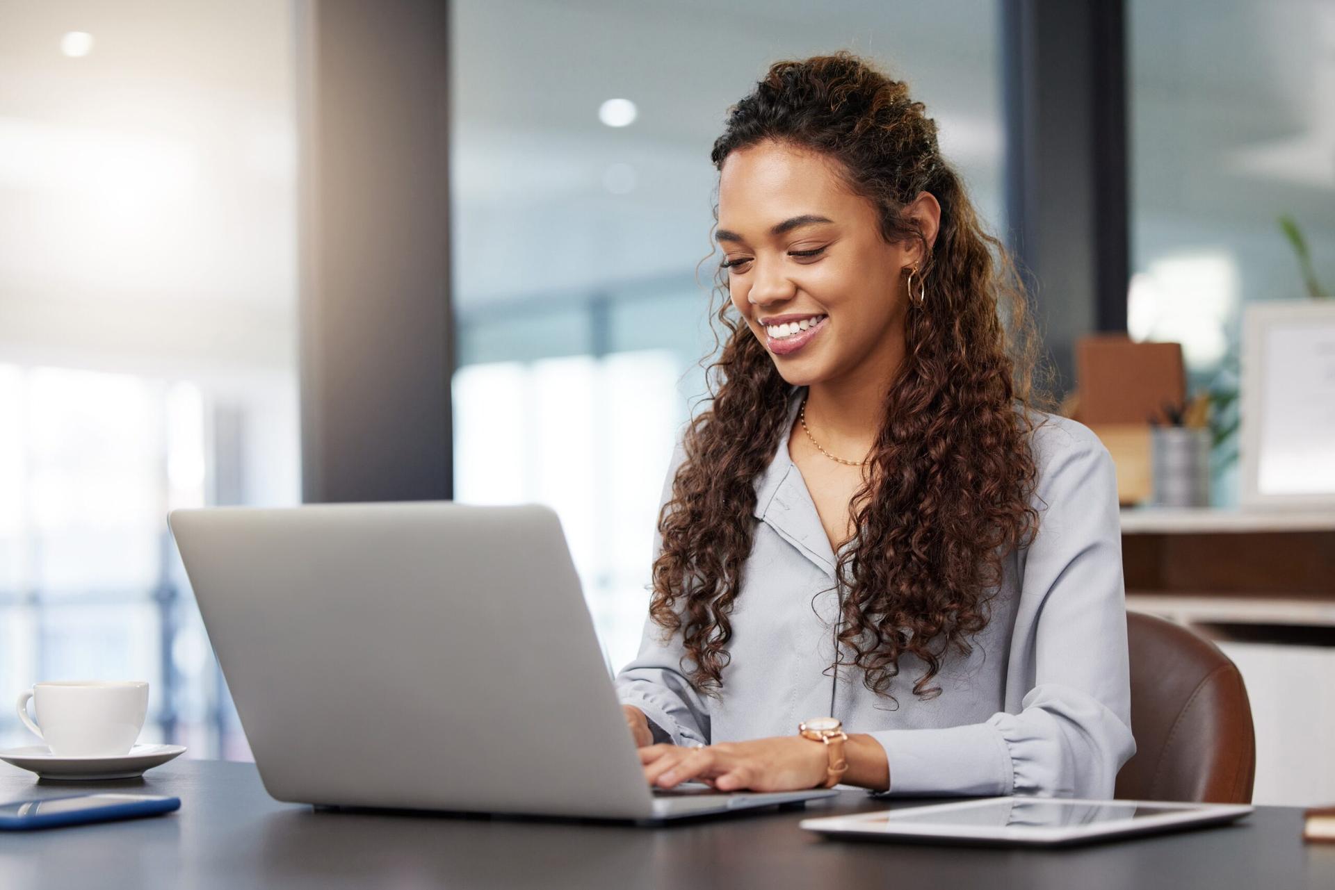 Woman smiling on a laptop in a window office